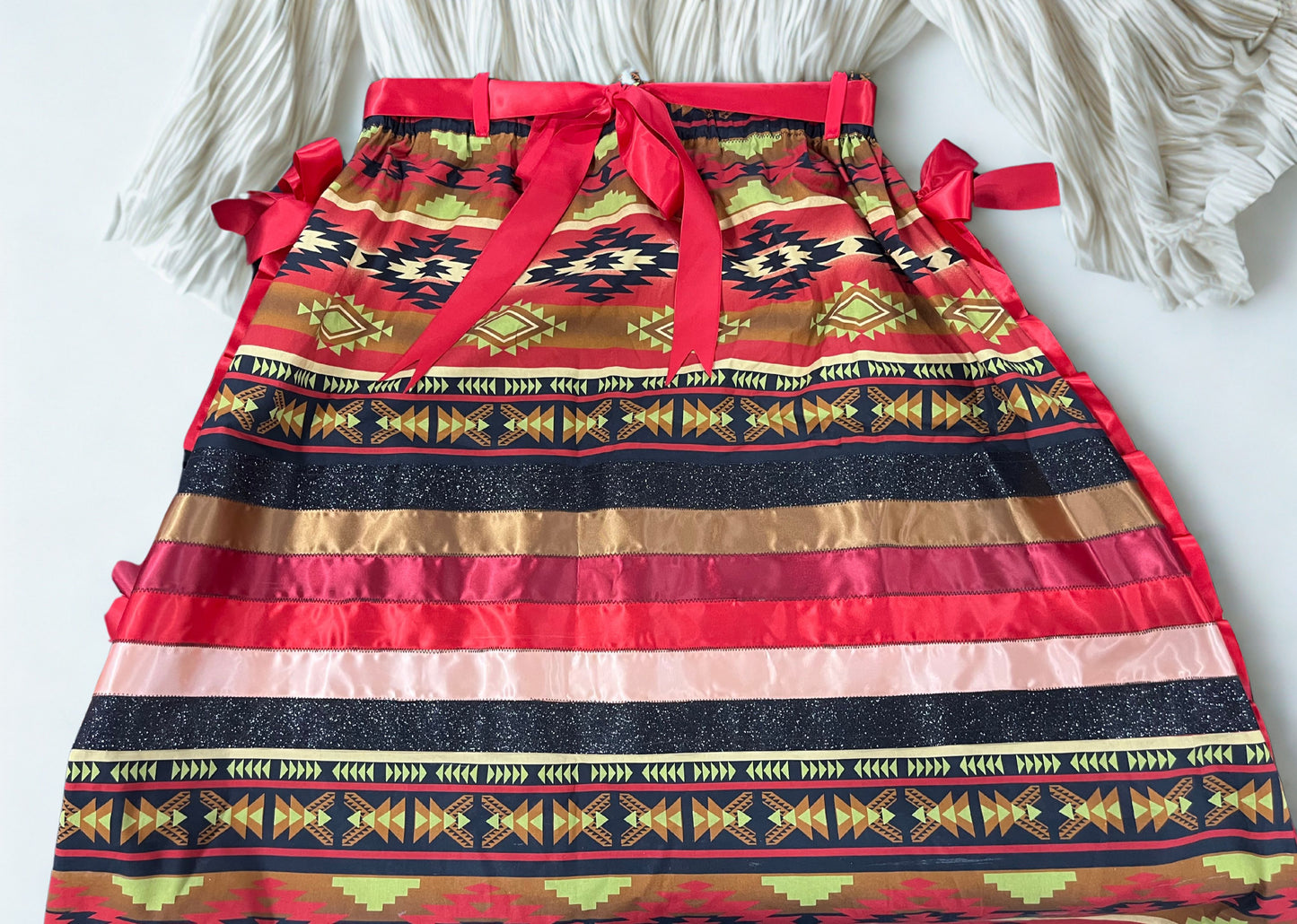 Colorful patterned skirt with red waistband and decorative bows on a white background