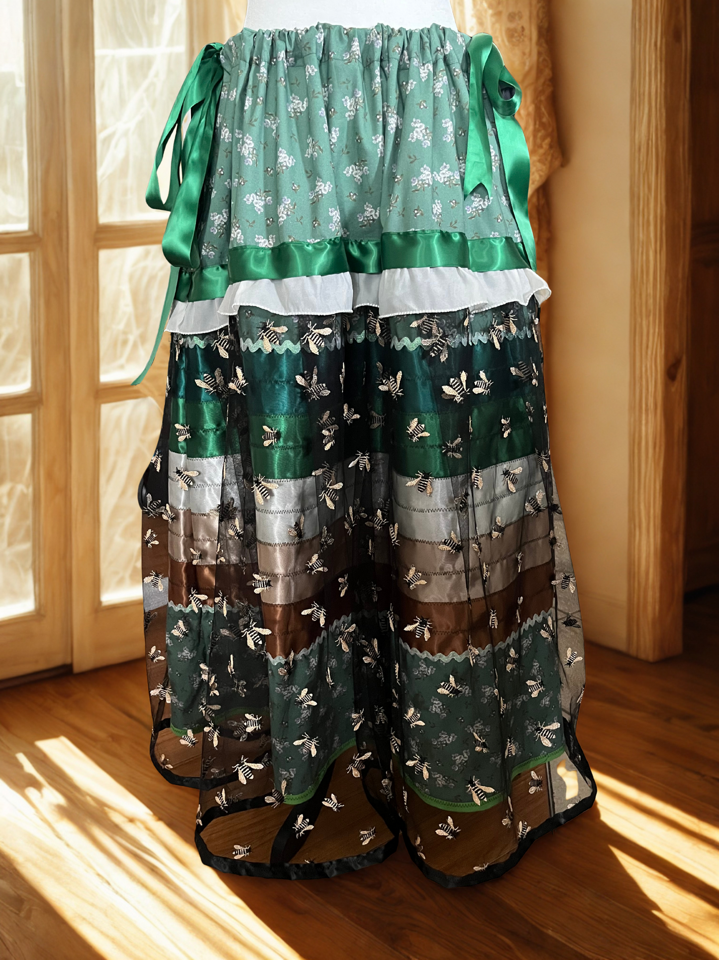 Green layered ribbon skirt with floral patterns on a wooden floor