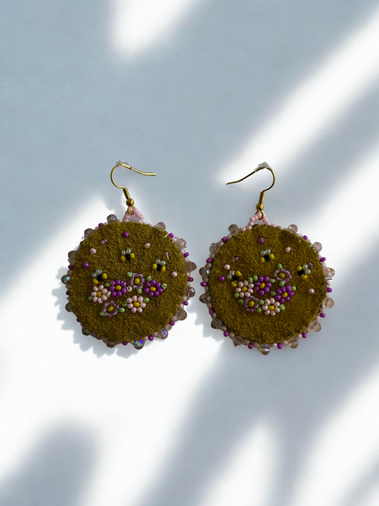 Pair of round earrings with floral details on a light background
