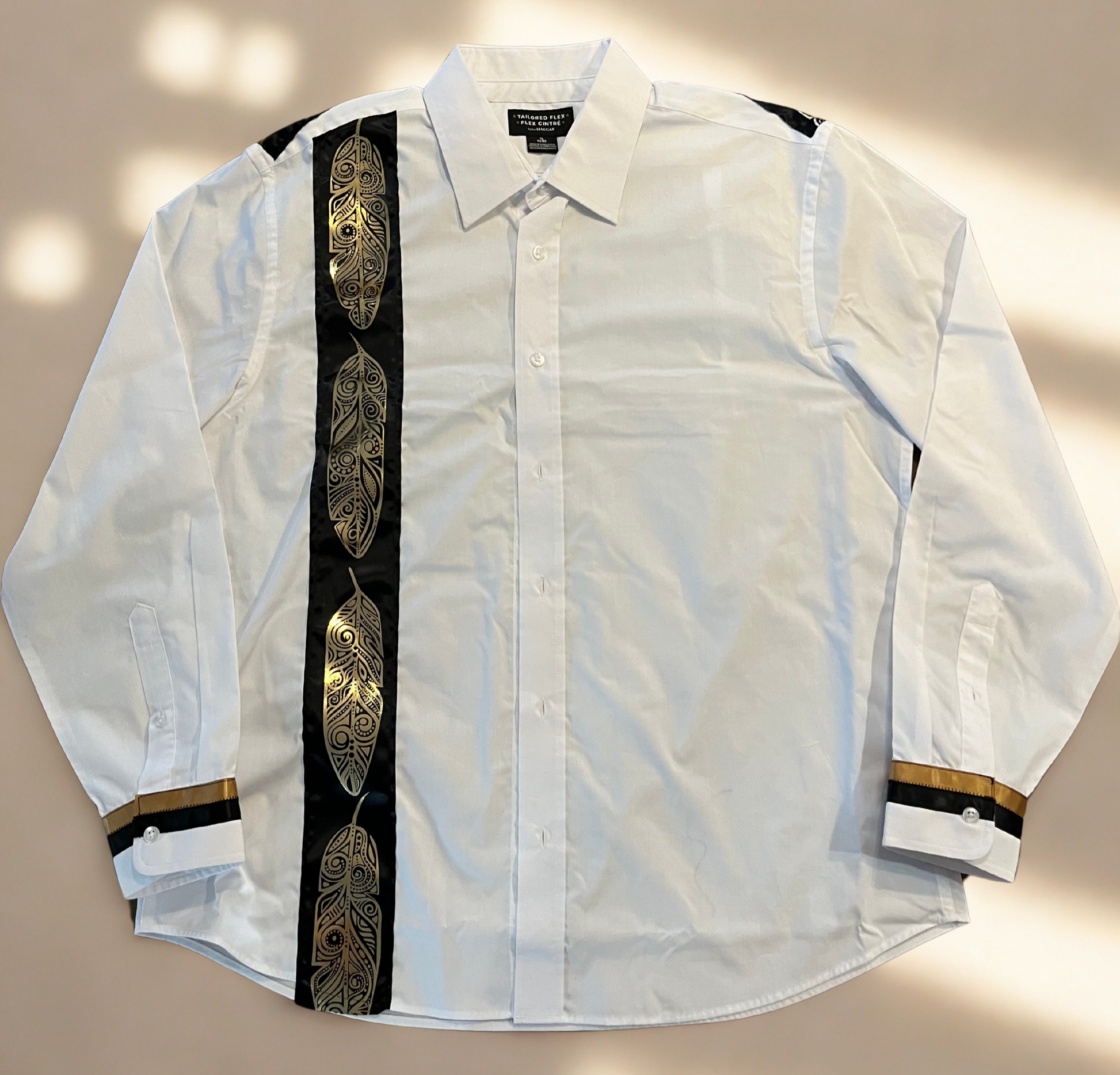 White shirt with black and gold feather patterns on a beige background