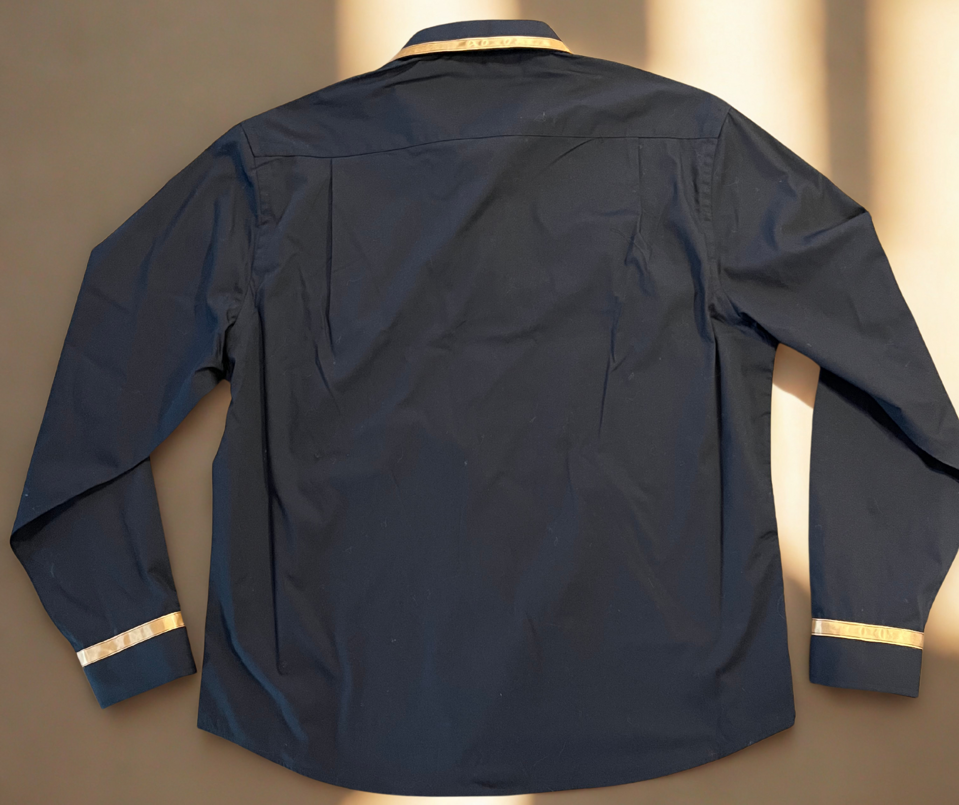 Black shirt with gold trim on a beige background