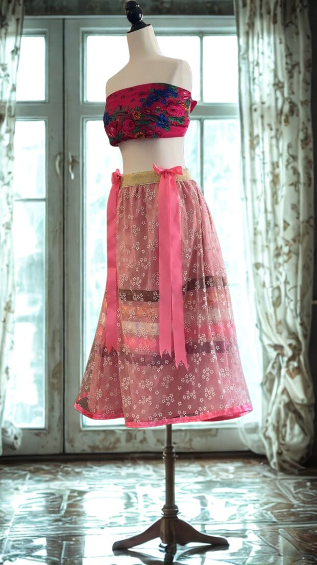 Mannequin wearing a colorful outfit with a floral top and pink skirt in front of a window.