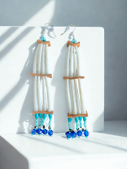 Pair of long earrings with white and blue beads on a light background