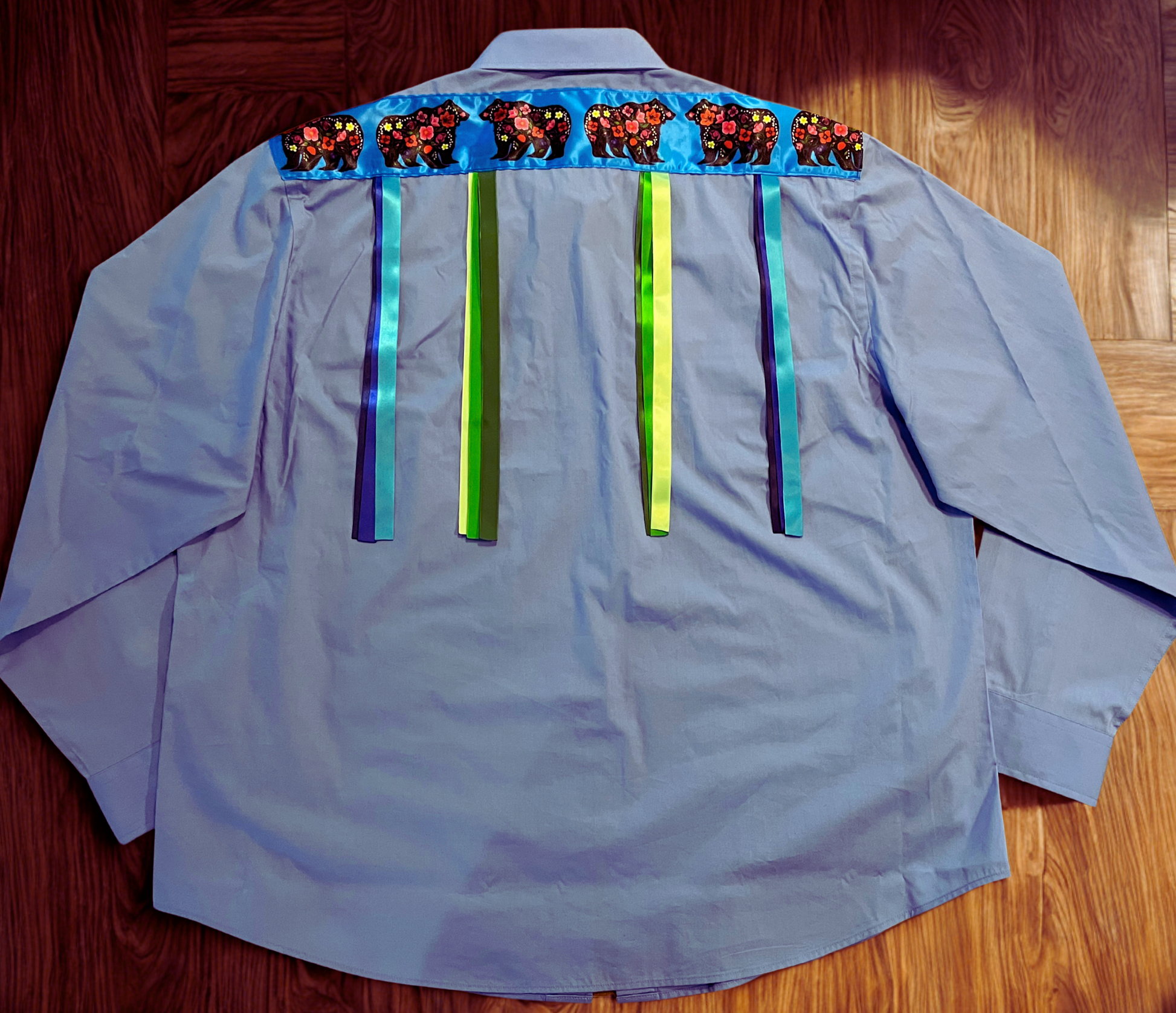 Light blue shirt with colorful decorative elements on a wooden surface