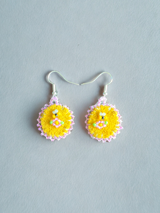 Pair of yellow and pink earrings on a light gray background