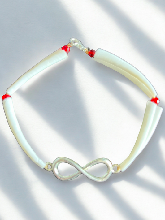 White dentalium shell bracelet with silver métis charm and red beads on a light background