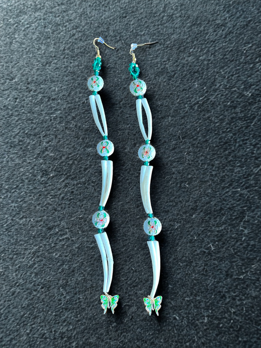Pair of long earrings with floral designs on a dark background