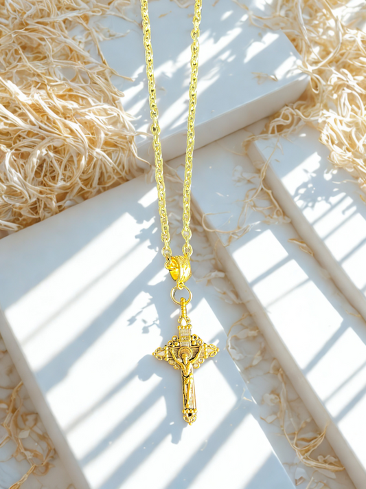Gold necklace with a cross pendant on a white surface with straw-like material.