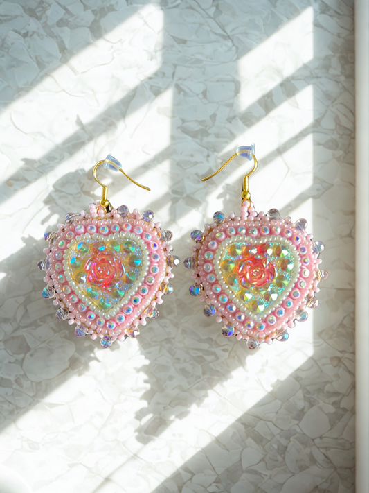 Heart-shaped earrings with colorful beadwork on a textured white surface