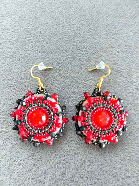 Pair of red and black beaded earrings on a gray background