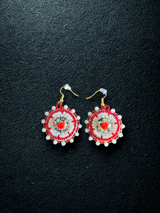 Pair of red and white earrings on a black background