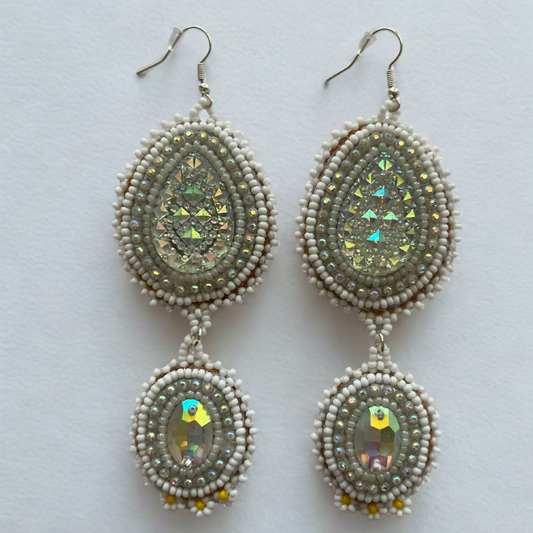 Pair of beaded earrings with reflective center on a light gray background