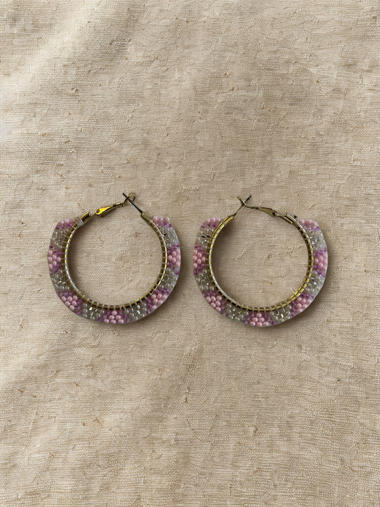 Hoop earrings with pink, white, and silver beads on a beige fabric background
